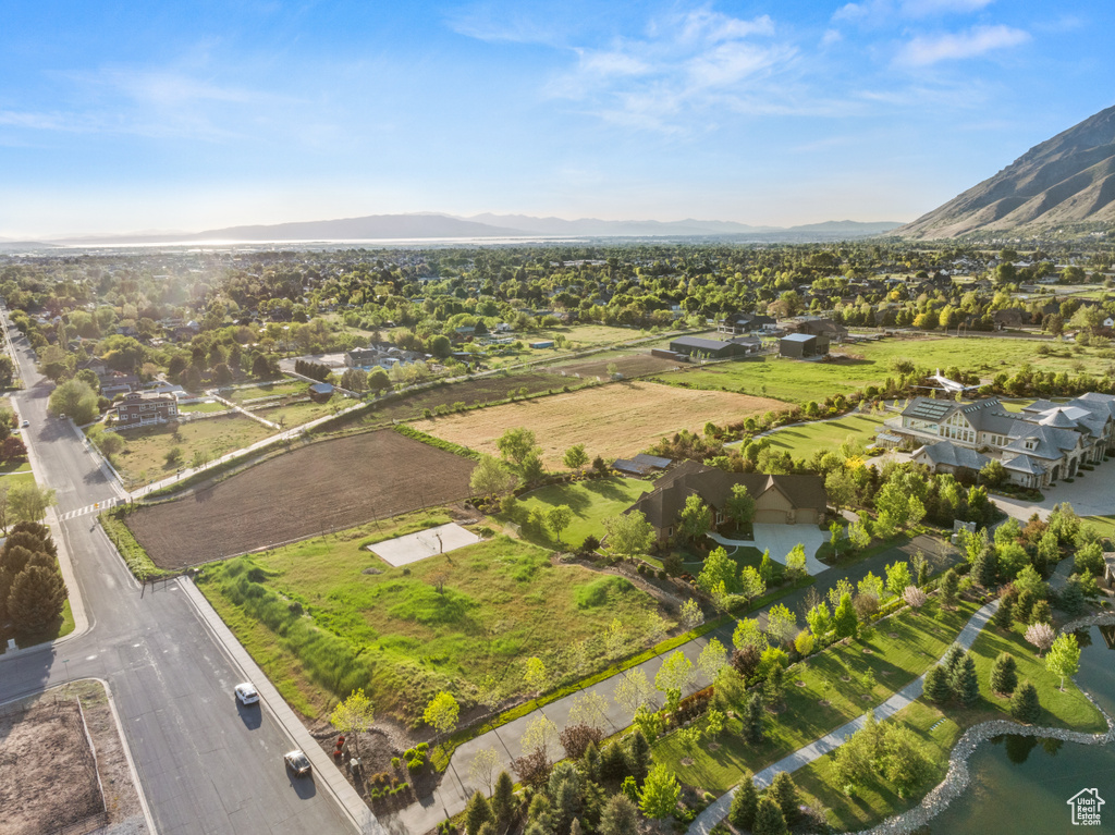 Aerial view of property and surrounding area featuring nearby suburban area and a water and mountain view
