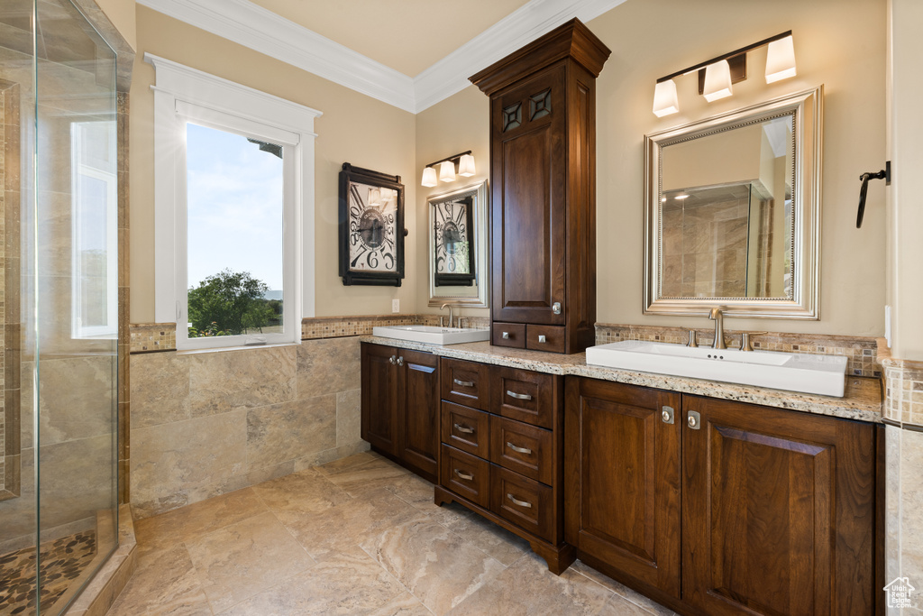Bathroom with tile walls, tiled shower, crown molding, double vanity, and wainscoting