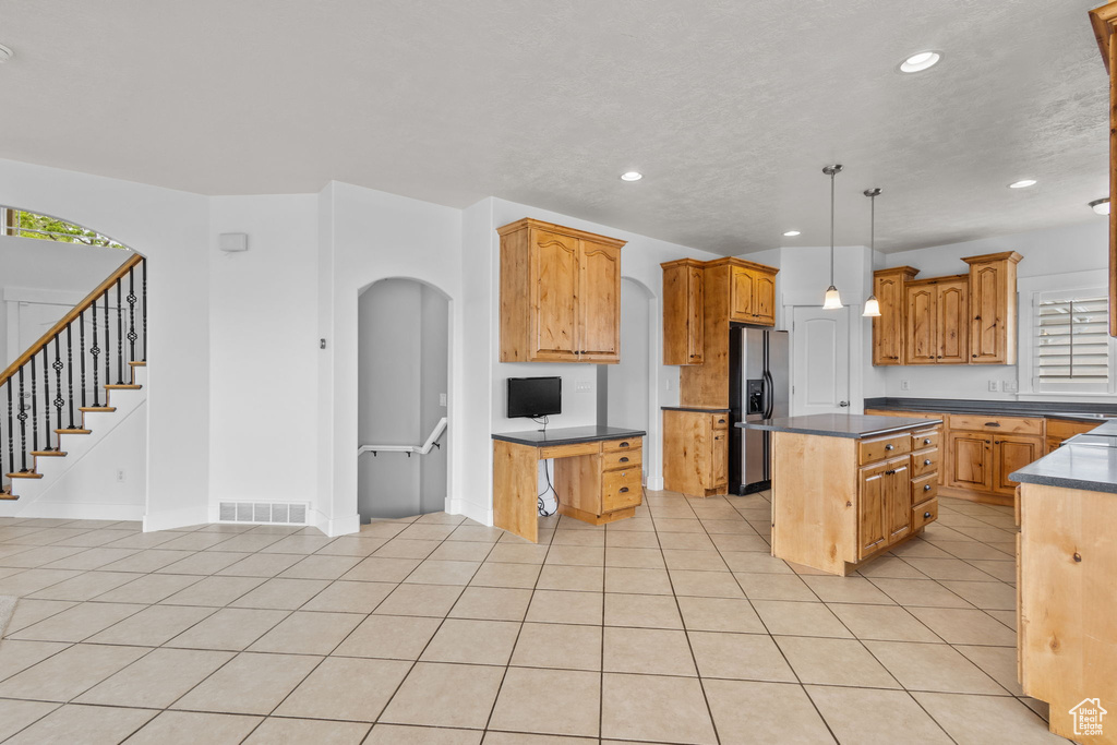 Kitchen with stainless steel fridge, dark countertops, recessed lighting, a kitchen island, and decorative light fixtures