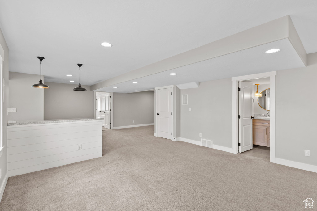 Unfurnished living room with light colored carpet, recessed lighting, baseboards, and a sink