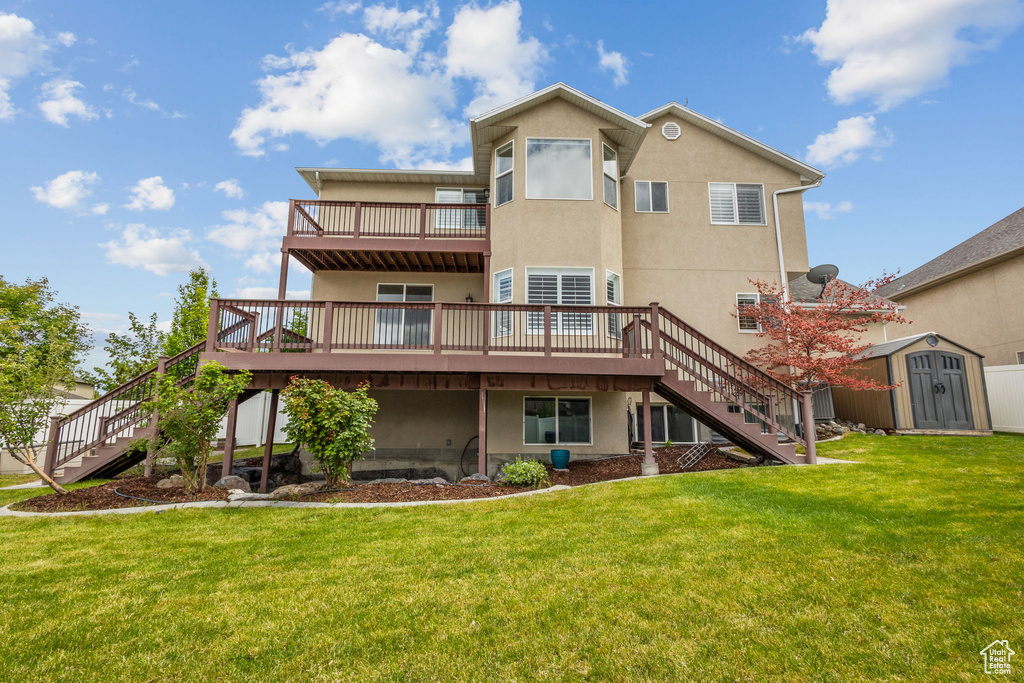 Back of house featuring stairway, a storage shed, a deck, and stucco siding
