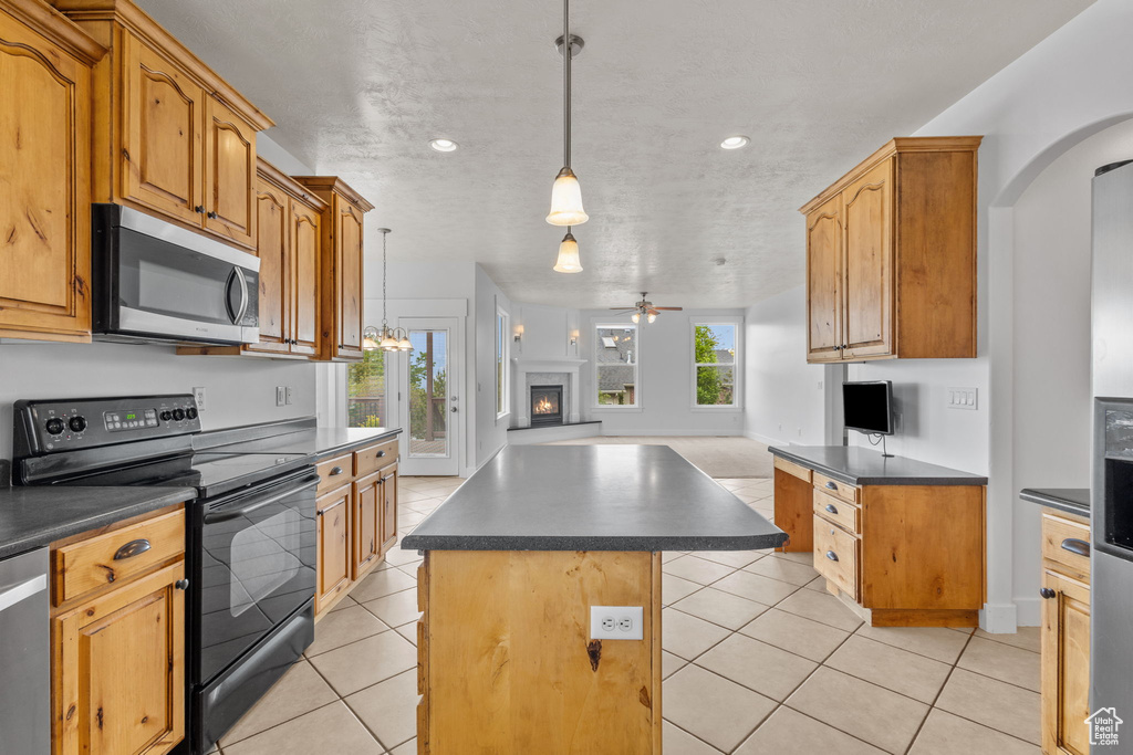 Kitchen featuring appliances with stainless steel finishes, dark countertops, open floor plan, ceiling fan, and arched walkways