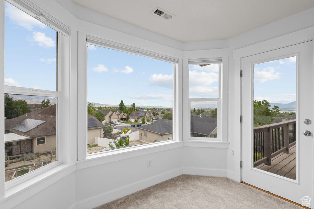 Unfurnished sunroom with carpet floors, plenty of natural light, and baseboards