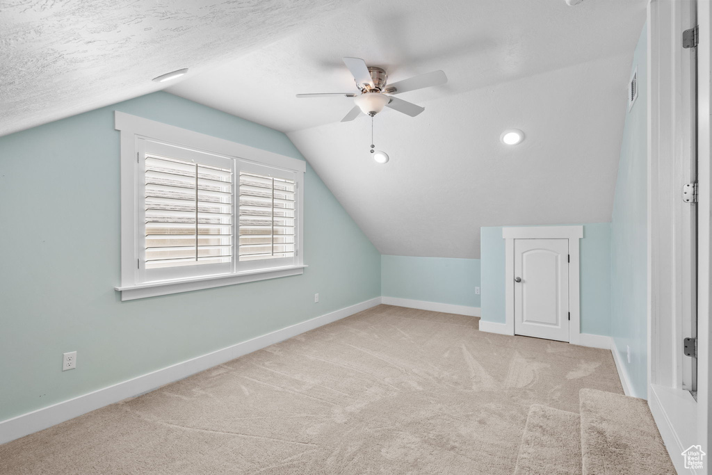 Bonus room with a ceiling fan, lofted ceiling, carpet floors, and baseboards