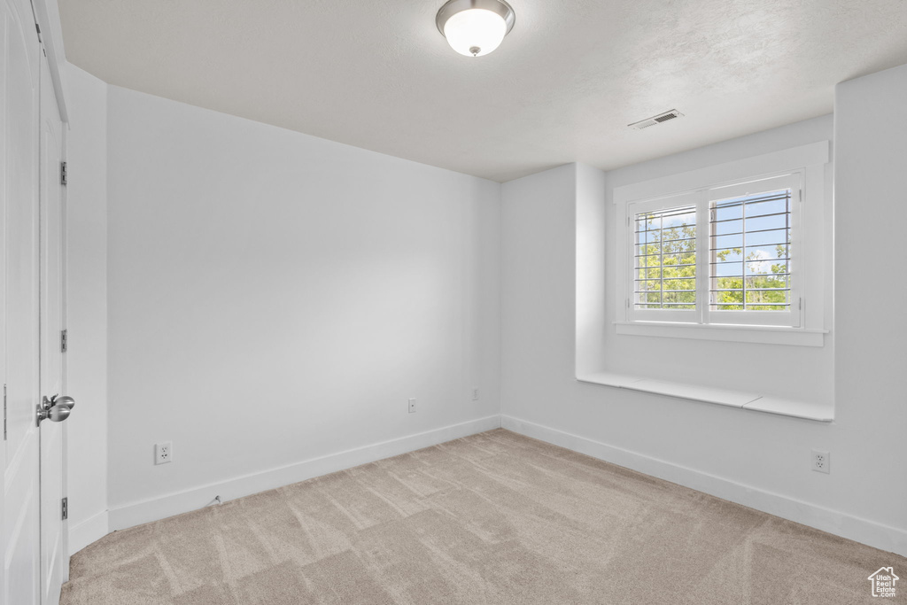Carpeted spare room featuring baseboards