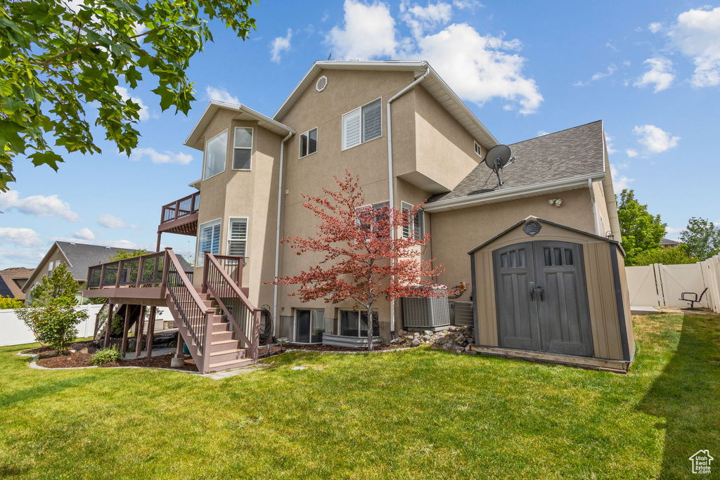 Rear view of property featuring stucco siding, a wooden deck, central air condition unit, a shed, and stairway