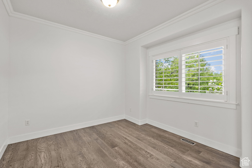 Unfurnished room featuring crown molding, wood finished floors, and baseboards