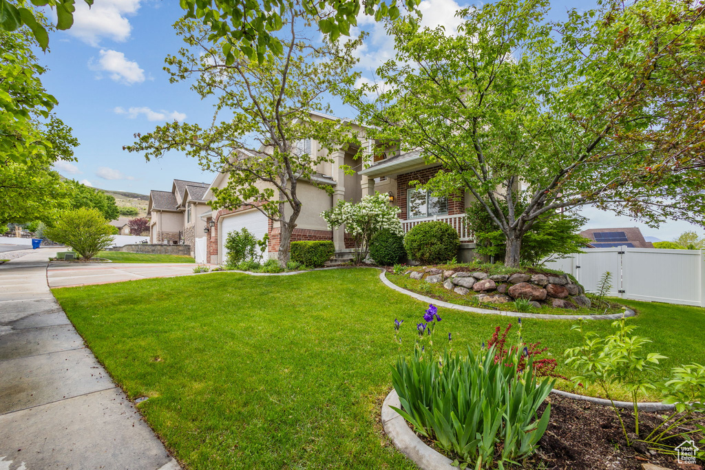 View of property hidden behind natural elements featuring concrete driveway, a garage, brick siding, and stucco siding