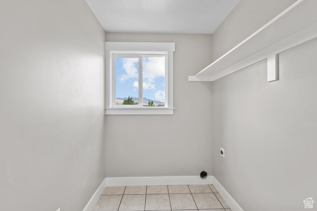 Laundry area with baseboards, hookup for an electric dryer, and light tile patterned floors