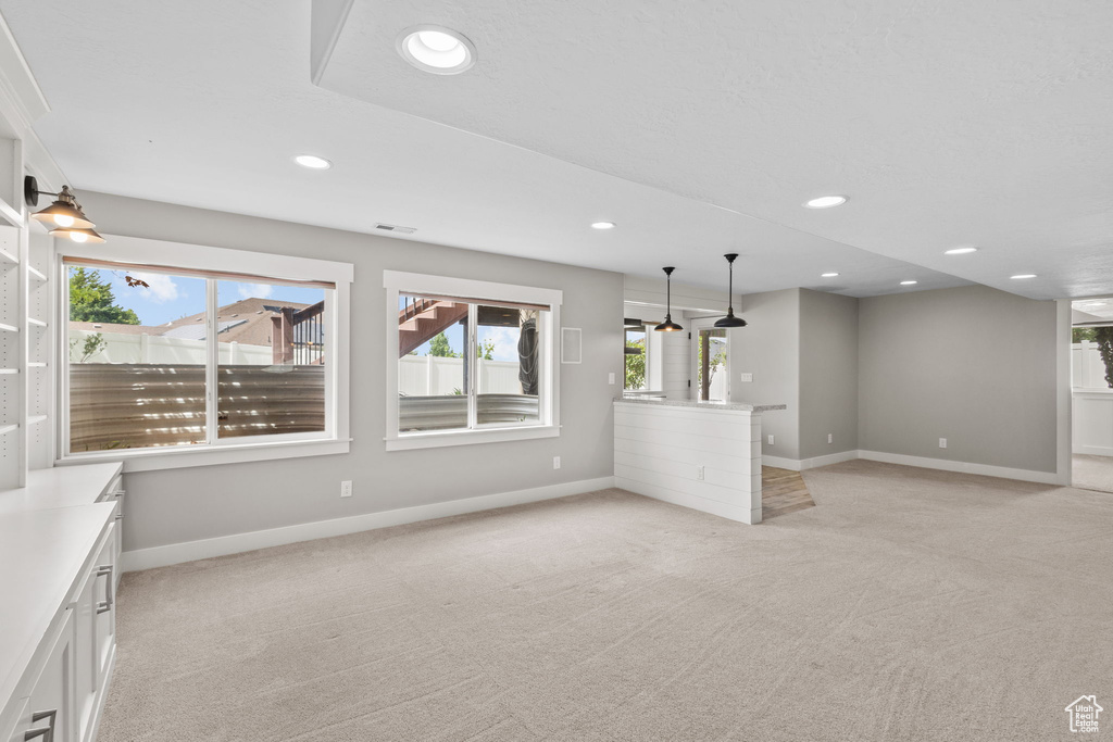 Unfurnished living room with light carpet, baseboards, and recessed lighting