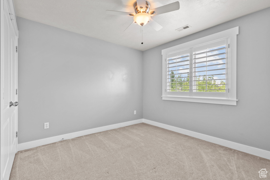 Carpeted empty room with baseboards and a ceiling fan