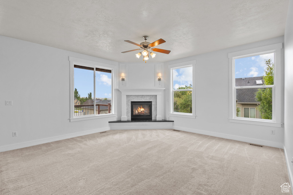 Unfurnished living room featuring baseboards, ceiling fan, and carpet flooring