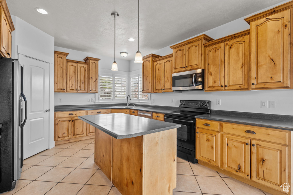 Kitchen with appliances with stainless steel finishes, a sink, light tile patterned flooring, a center island, and recessed lighting