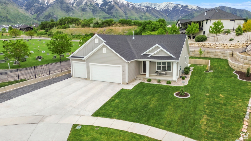 Ranch-style home featuring concrete driveway, an attached garage, board and batten siding, a mountain view, and a porch