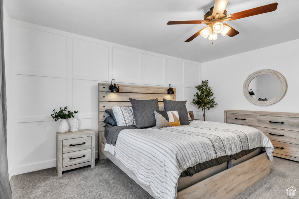 Bedroom with light colored carpet, a decorative wall, and a ceiling fan