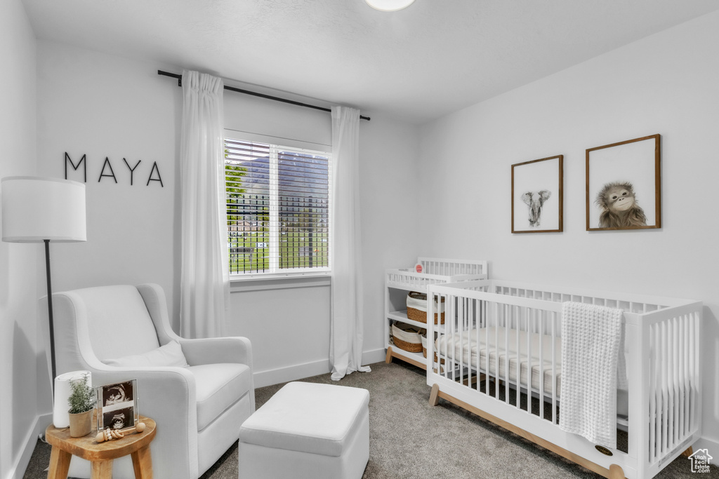 Carpeted bedroom with a crib and baseboards