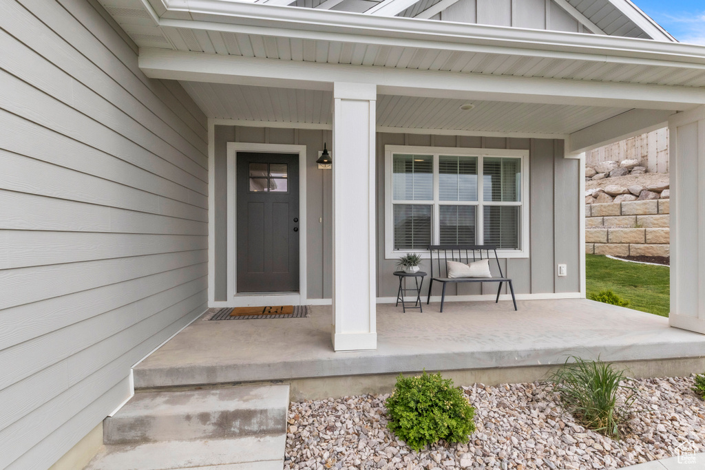 Doorway to property with covered porch and board and batten siding