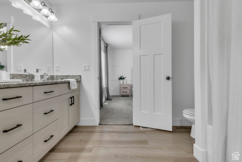 Bathroom featuring wood finished floors, toilet, vanity, and baseboards