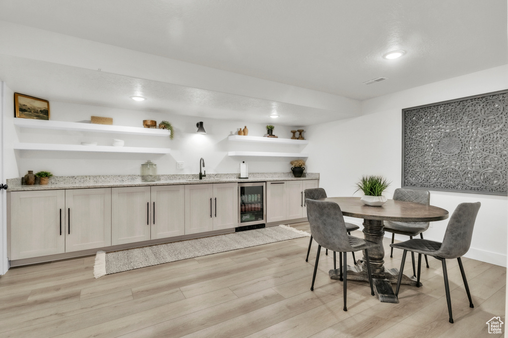 Dining room with beverage cooler, wet bar, and light wood-style flooring