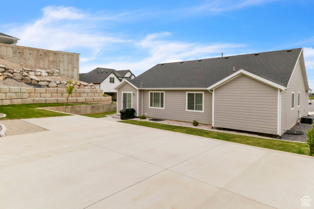 Rear view of property featuring a patio area, roof with shingles, and cooling unit