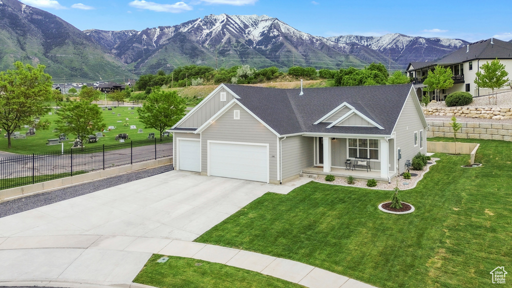 View of front of house with an attached garage, driveway, a porch, a mountain view, and a shingled roof