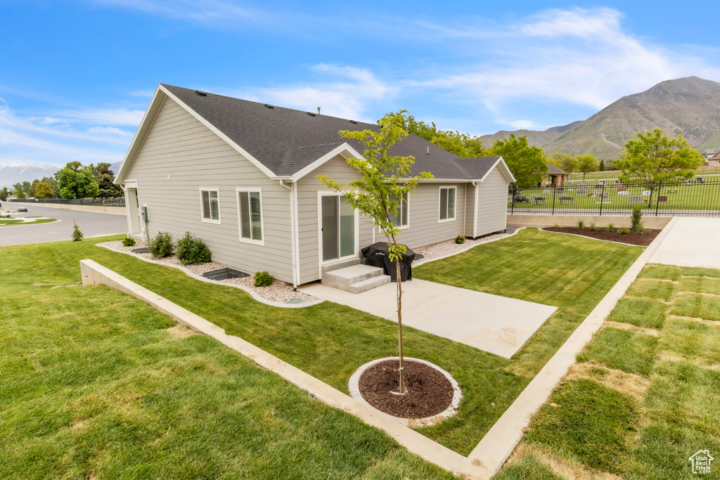 Rear view of property with a mountain view, a patio area, and a shingled roof