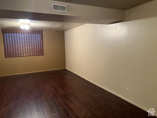 Spare room featuring dark wood-style floors and baseboards