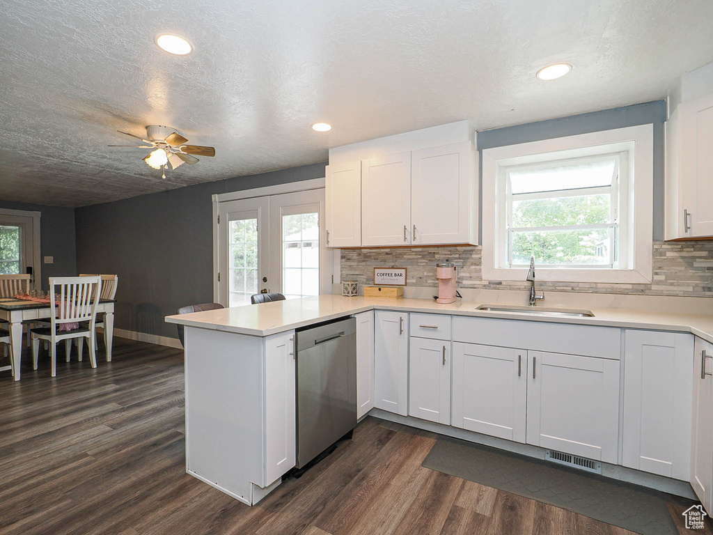 Kitchen with dishwasher, a sink, a peninsula, dark wood finished floors, and plenty of natural light