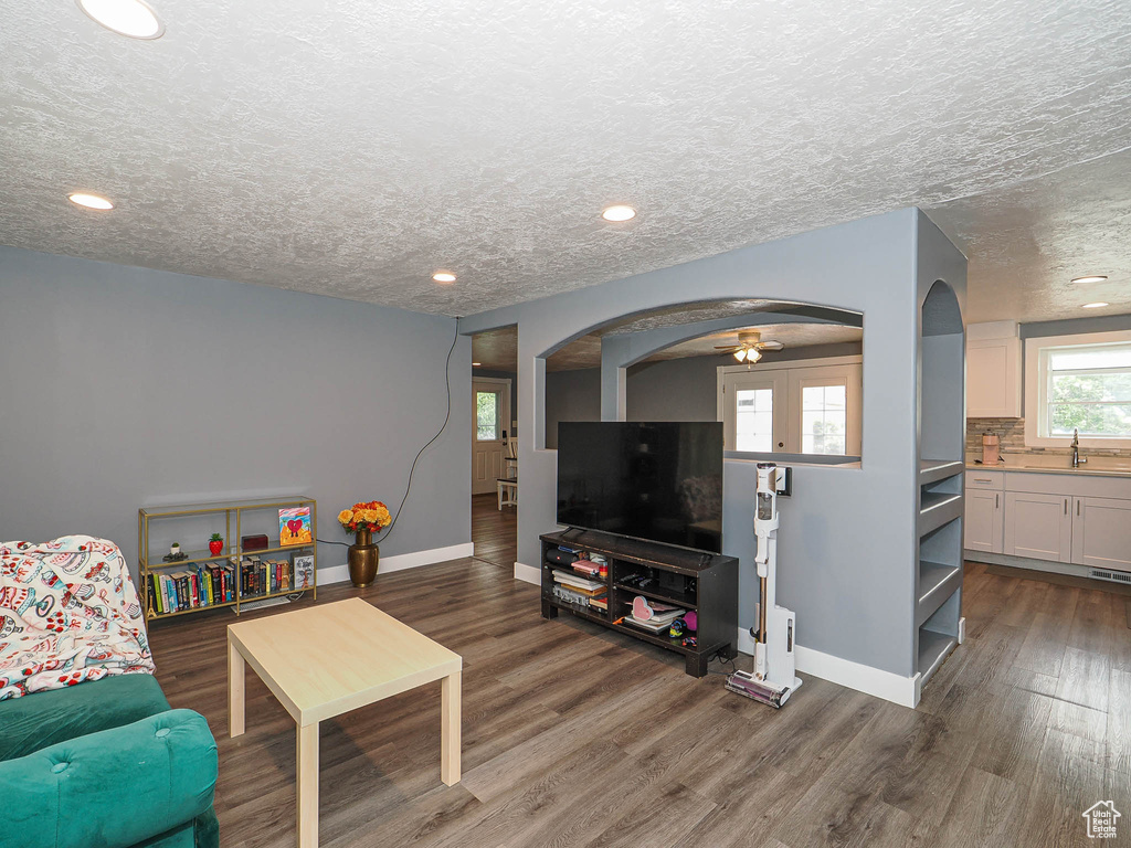 Living area with arched walkways, baseboards, a ceiling fan, wood finished floors, and recessed lighting
