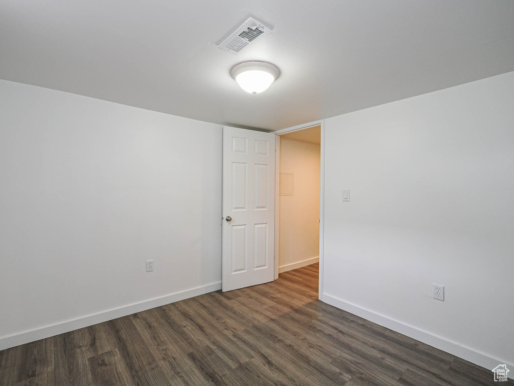 Spare room featuring dark wood-type flooring and baseboards