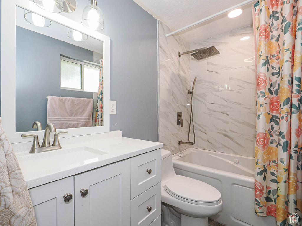 Bathroom featuring shower / tub combo, toilet, and vanity