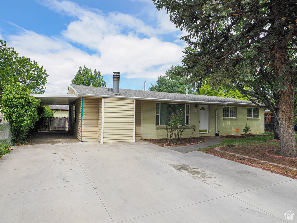 Ranch-style house featuring driveway, a carport, brick siding, and fence