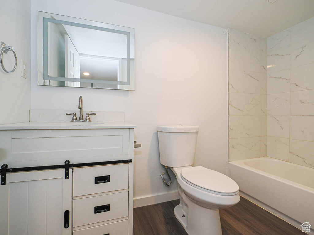 Bathroom with wood finished floors, baseboards, toilet, and vanity