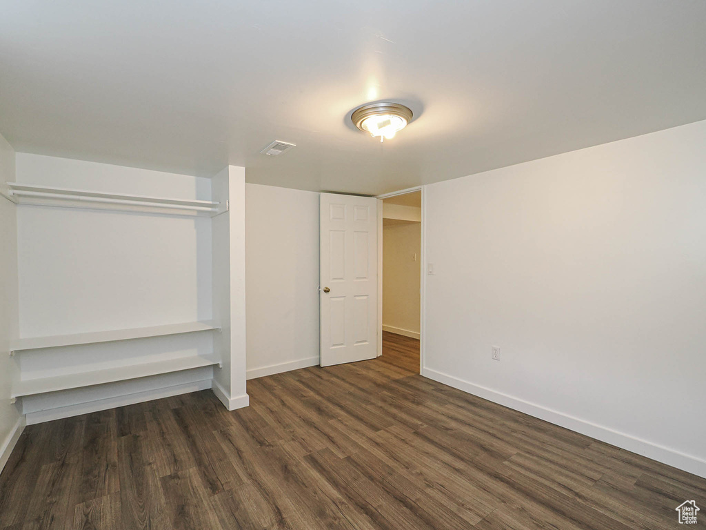 Unfurnished bedroom with dark wood-style floors, baseboards, and a closet