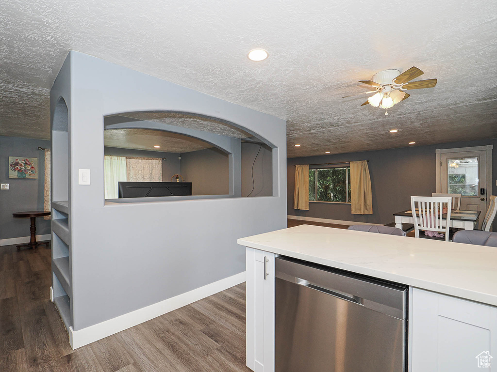 Kitchen with dishwasher, white cabinetry, dark wood-style flooring, a ceiling fan, and a textured ceiling