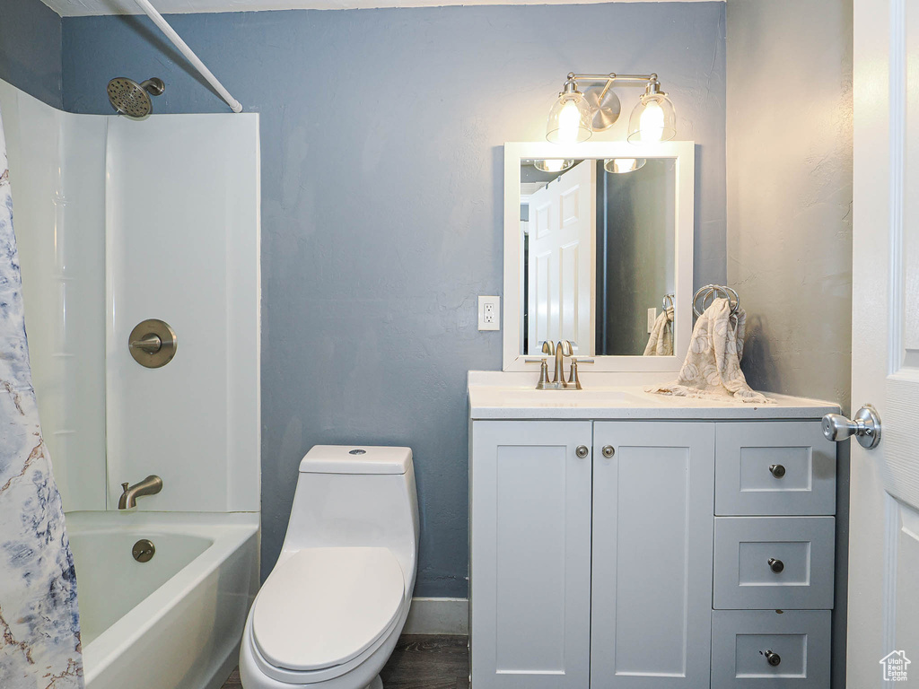 Full bath with toilet, shower / bathtub combination with curtain, vanity, and baseboards