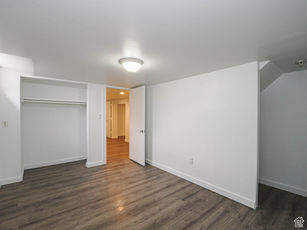 Unfurnished bedroom featuring a closet, dark wood-style floors, and baseboards