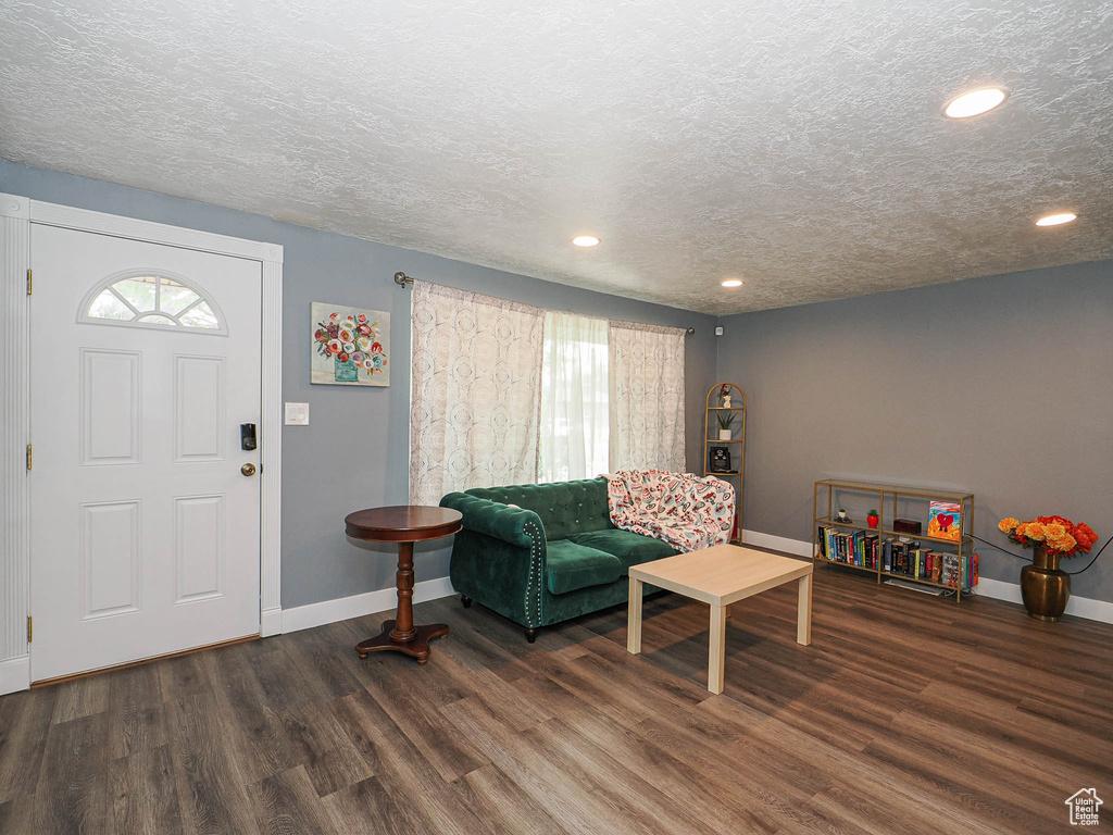 Living area with baseboards, wood finished floors, a textured ceiling, and recessed lighting