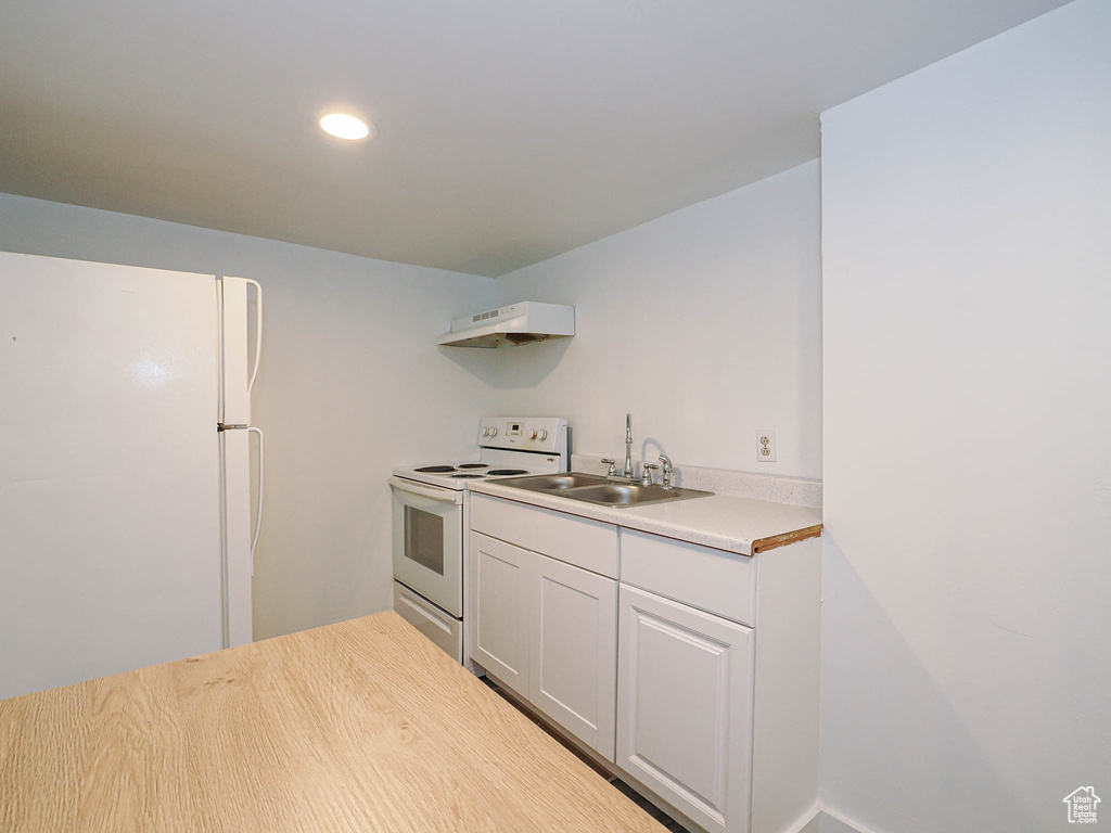 Kitchen with white appliances, a sink, under cabinet range hood, light countertops, and recessed lighting