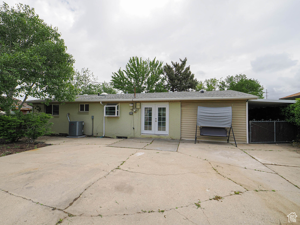 Back of property with french doors, central AC unit, driveway, an attached carport, and brick siding