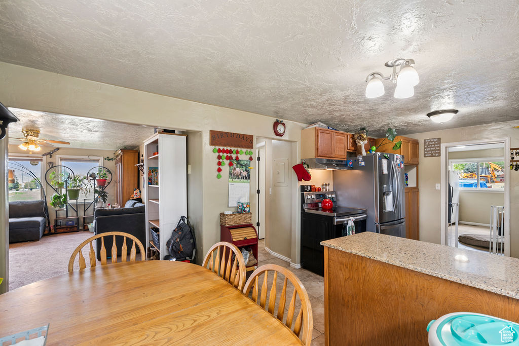 Dining space with plenty of natural light, a textured ceiling, a ceiling fan, and a chandelier