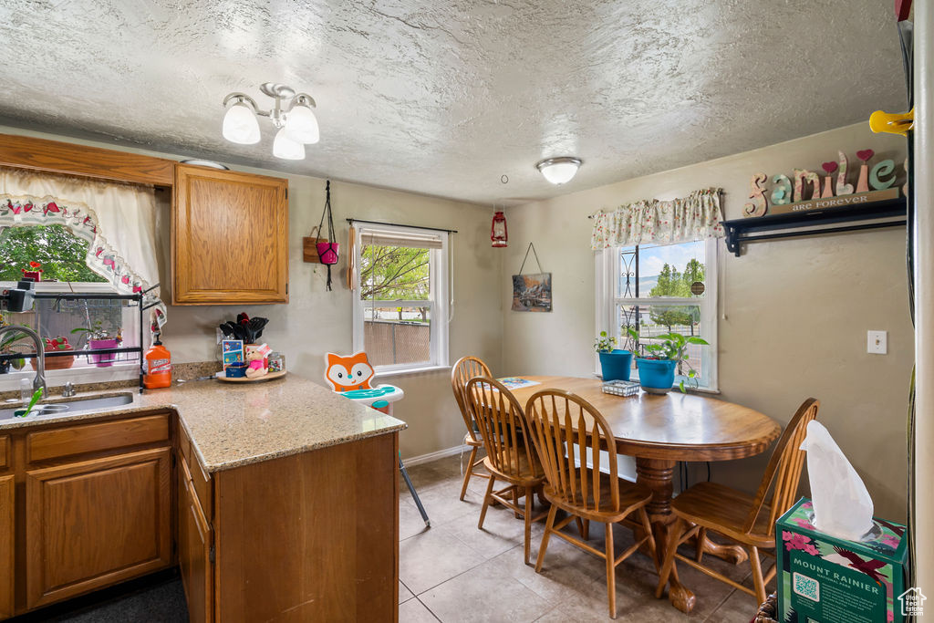 Dining space with light tile patterned flooring, baseboards, and a textured ceiling