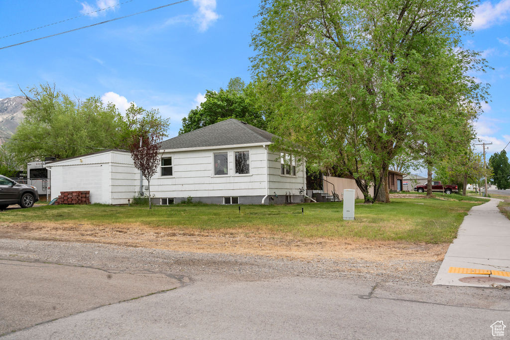 View of front of house featuring a front lawn and a shingled roof