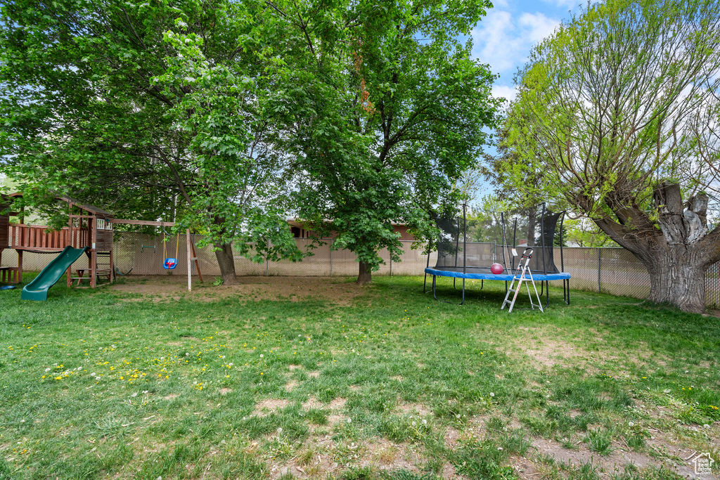 View of yard with a trampoline and a playground