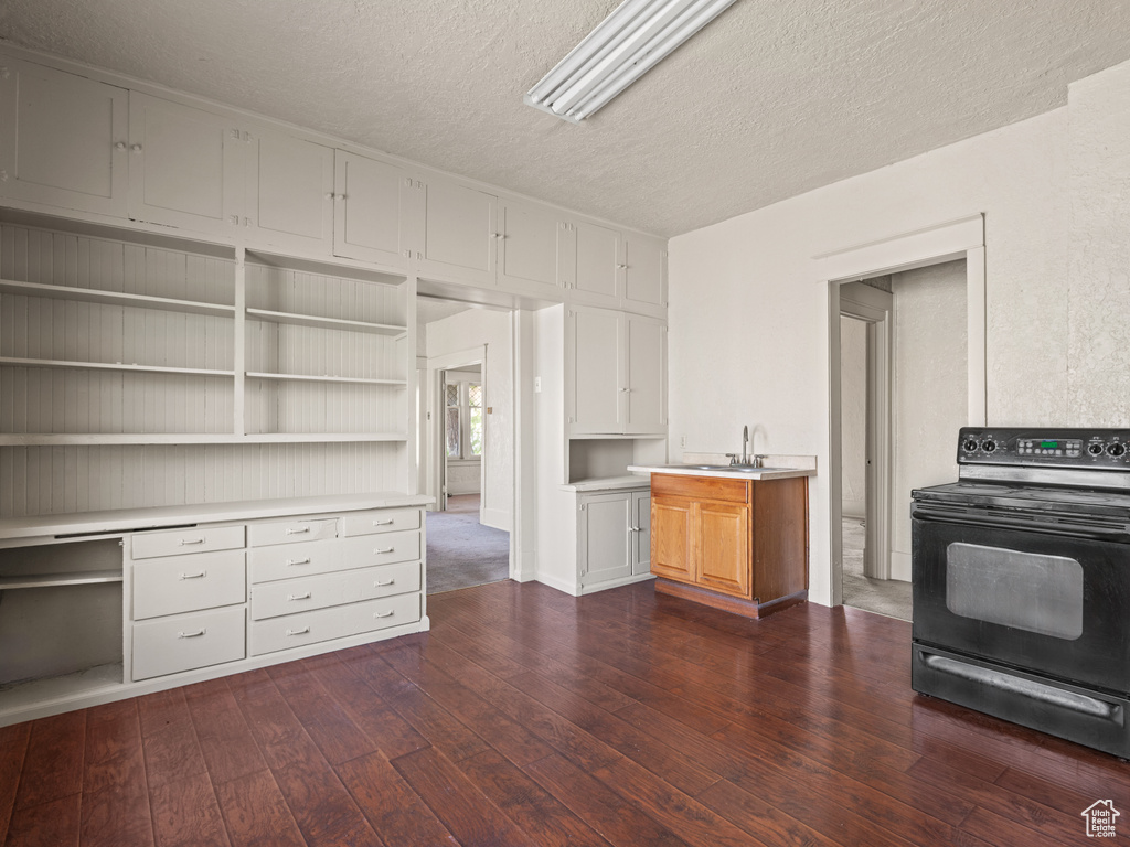 Kitchen with electric range, a textured ceiling, dark wood finished floors, open shelves, and light countertops