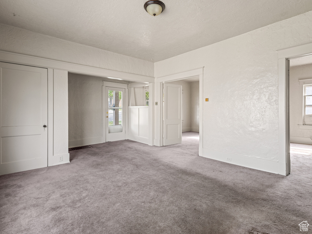 Carpeted spare room with a textured ceiling and a textured wall