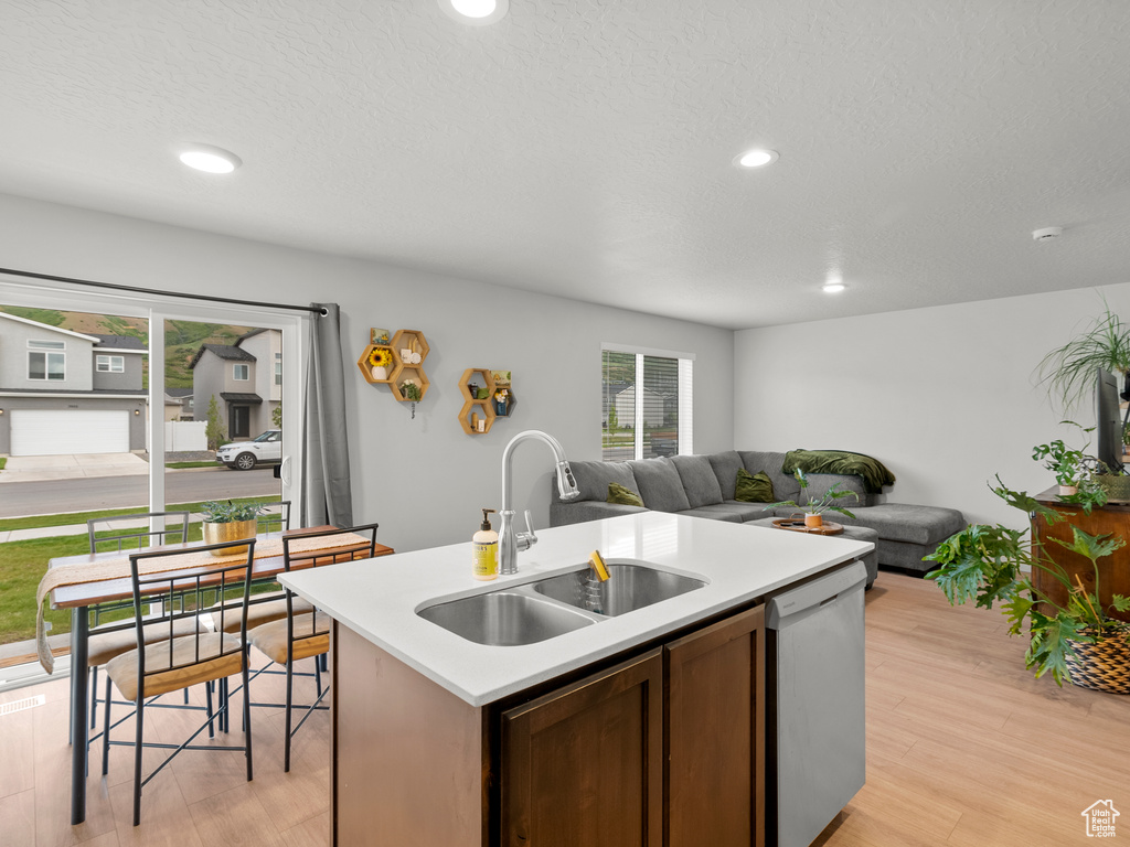 Kitchen featuring a sink, dishwasher, light countertops, plenty of natural light, and recessed lighting