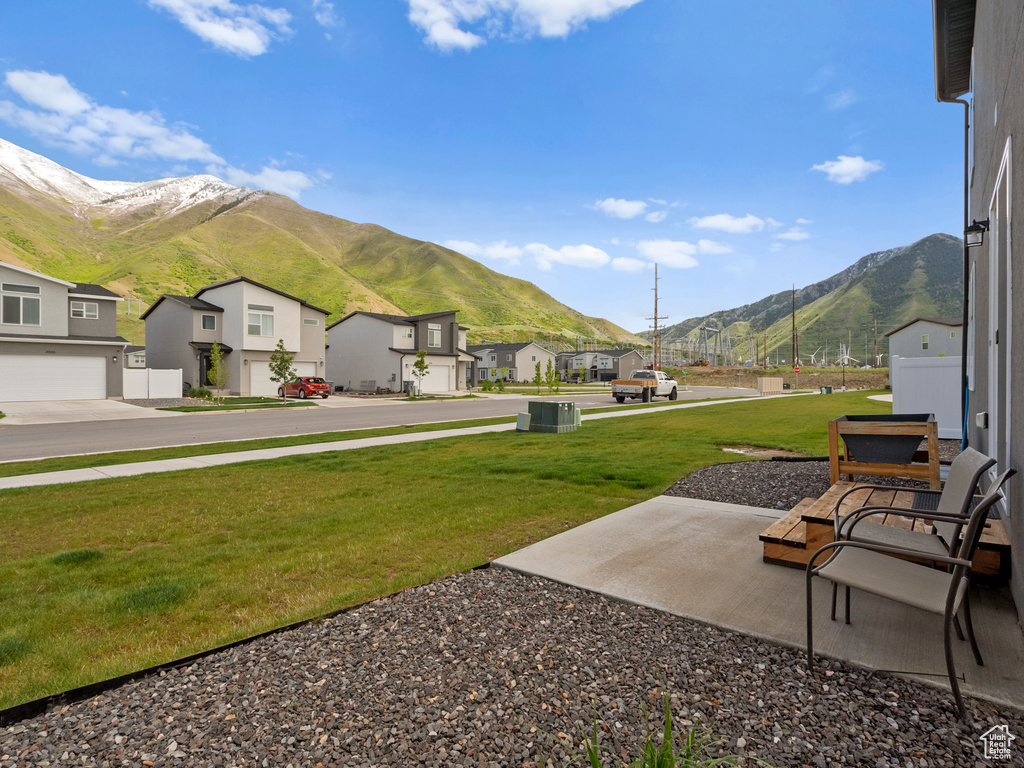 View of grassy yard with a residential view, a mountain view, and central AC unit