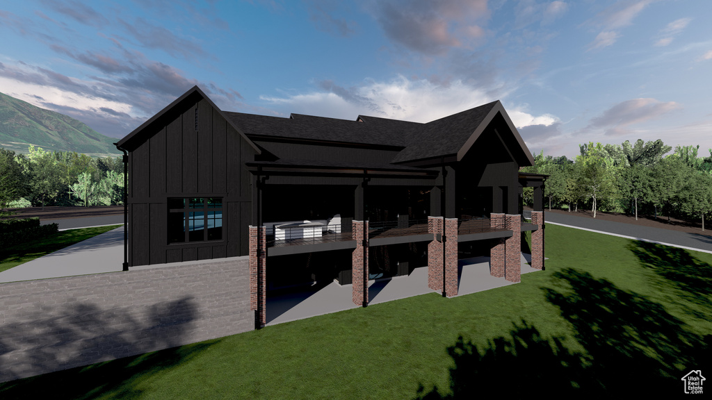 Rear view of house featuring board and batten siding, a balcony, a yard, and a mountain view