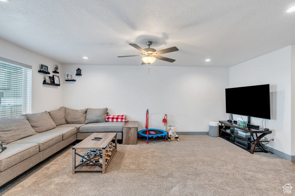 Carpeted living room featuring ceiling fan, a textured ceiling, recessed lighting, and baseboards